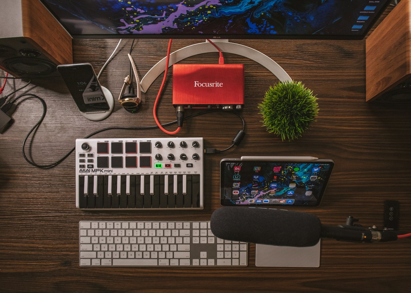 Sprzęt do produkcji muzycznej ułożony na ciemnym drewnianym biurku.